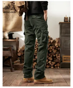 Back view of men's American retro olive green multi-pocket cargo pants in a rustic setting.