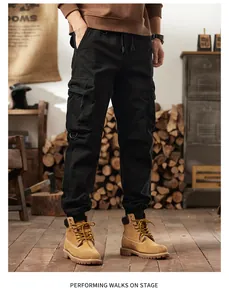 Black multi-pocket jogger cargo pants styled with tan work boots in a rustic setting.