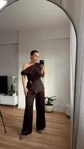 Ganzkörperansicht eines schokoladenbraunen One-Shoulder-Tops und einer weiten Hose im Set.