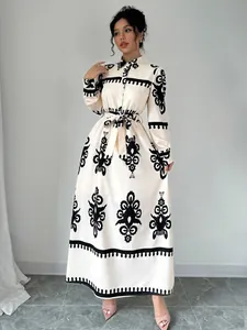 Full view of a cream long-sleeved shirt dress with black ethnic print and waist tie.