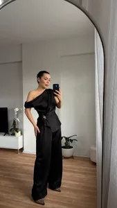 Elegantes schwarzes Satin-Set mit schulterfreiem Oberteil und weiter Hose.