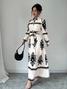 Woman wearing an elegant cream maxi shirt dress with black baroque style patterns