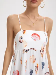 Close-up detail of a white summer camisole dress featuring vibrant seashell prints