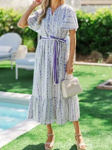 Model wearing a bohemian floral V-neck maxi dress with a purple ribbon belt and ruffle hem