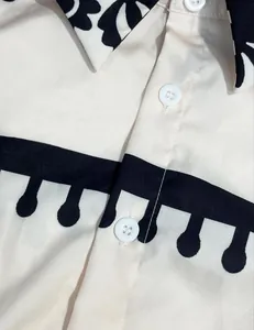 Macro detail view of white buttons and black graphic print on ivory shirt dress fabric