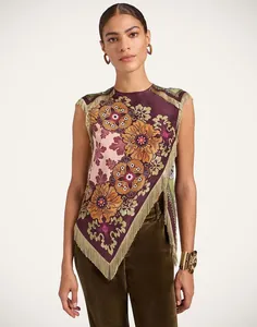 Detailopname van een bohemian asymmetrische top met bloemenprint en lange franjes.
