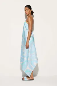 Side view of a printed satin halter dress with an asymmetrical hem and matching sandals