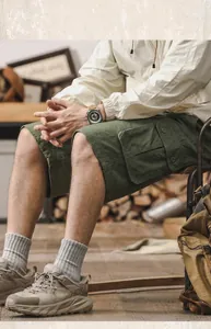 Detailed shot of men's olive green cotton cargo shorts in a rustic lifestyle setting