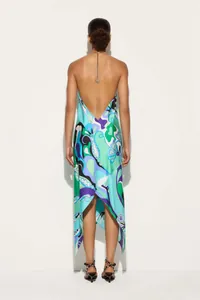Back view of a vibrant satin print halter dress with a backless design and irregular hem