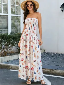 Full length view of a smocked shell print bandeau maxi dress in a sunny outdoor setting.