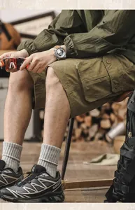 Lifestyle detail of men's olive green cotton cargo shorts in a rustic setting.