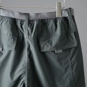 Detail of men's quick-dry cargo pants with waistband and flap pockets.