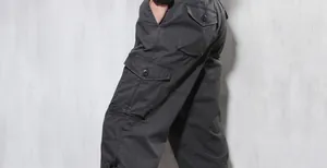 Side detail of men's loose cargo pants with large buttoned pockets and hem drawstring.
