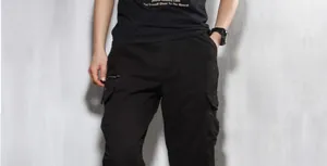 Detailed view of men's loose black cargo pants with multiple functional pockets.
