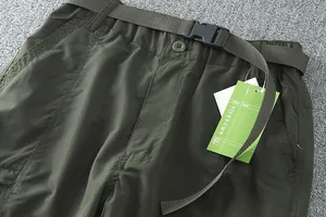 Gros plan d'un pantalon cargo vert avec ceinture en toile et détail de boucle.