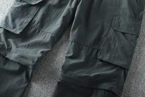Close-up detail of durable fabric and cargo pocket on dark grey men's outdoor pants