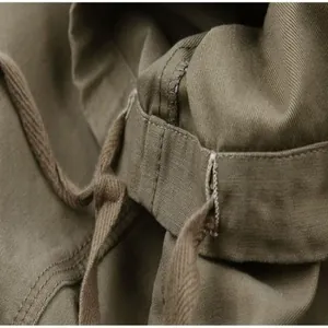 Detail view of the elastic waistband and drawstring on olive green cargo pants.