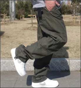 Side view detail of loose olive green multi-pocket cargo pants with functional design