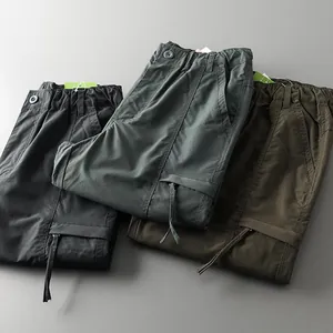 Detail view of folded men's outdoor cargo pants in grey, dark green, and olive