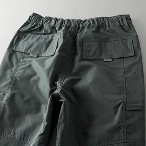 Detailed view showing the back flap pockets and elastic waistband on dark outdoor pants