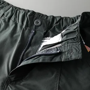 Detailed view of the elastic waistband and zipper fly on dark gray outdoor tactical pants