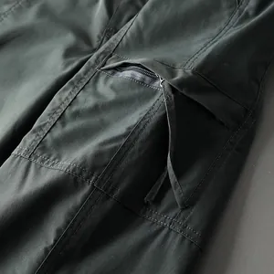 Detailed macro view of tactical cargo pants showing zippered pocket and durable fabric