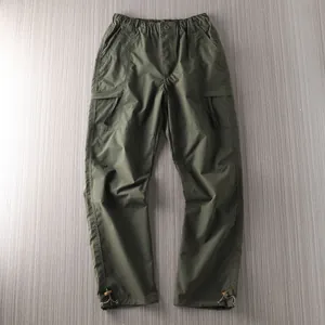 Detail view of men's olive green outdoor cargo pants with multi-pockets and adjustable hems
