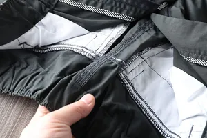 Detailed view of internal stitching, elastic waist and white pocket lining of men's outdoor pants.