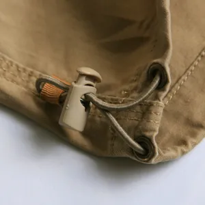 Dettaglio macro del fermacorda e del cordino su tessuto cargo kaki