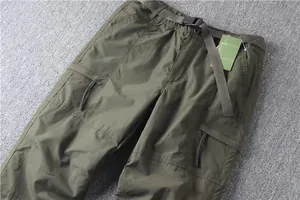 Close-up detail of men's olive green multi-pocket cargo pants with built-in belt