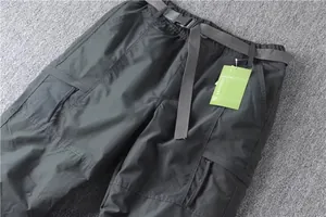 Detail view of men's dark grey straight cargo pants featuring built-in belt and pockets