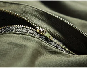 Macro-opname van het duurzame metalen ritsdetail op de olijfgroene katoenen cargobroek voor heren
