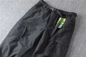 Detailed macro view of black multi-pocket cargo pants with tactical belt and tag