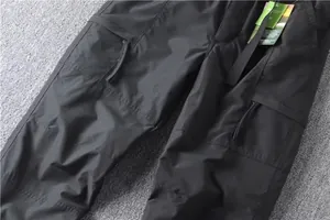 Detailed macro view of black multi-pocket cargo pants showing fabric and zippers