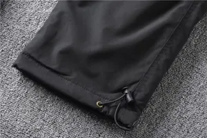 Detail view of black fleece cargo pants featuring adjustable drawstring hem and toggle lock.