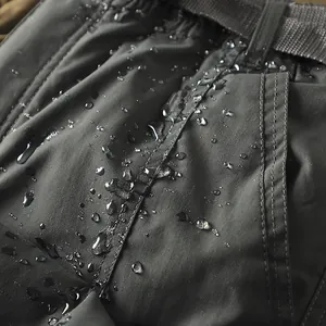 Dettaglio ravvicinato del tessuto impermeabile grigio scuro dei pantaloni da trekking