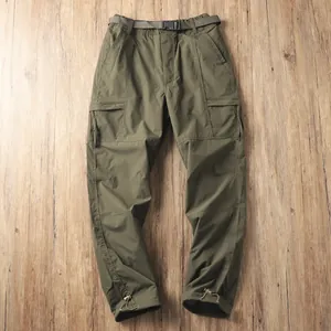 Dettaglio di pantaloni cargo da uomo impermeabili verde militare su fondo in legno