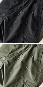 Close-up of waterproof fabric detail on outdoor cargo pants in black and green.