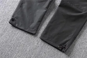 Detail of black cargo pants with adjustable drawstring hem for versatile fit and style.
