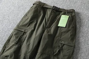 Close-up of men's olive green outdoor cargo pants with belt and pocket details