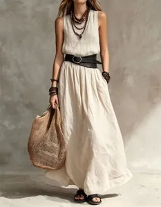 Elegant bohemian style sleeveless linen maxi dress in beige with belt and woven bag.
