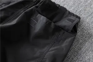 Close-up view of durable black tactical cargo pants showing velcro pocket closures.