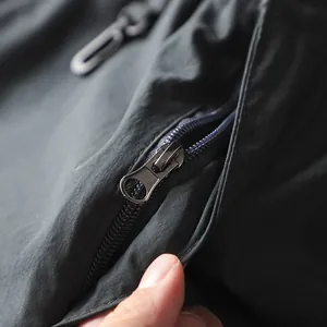 Dettaglio ravvicinato della cerniera metallica su pantaloni cargo da esterno traspiranti
