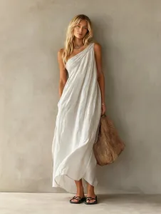Elegant white one-shoulder draped maxi dress styled with a summer woven straw bag.