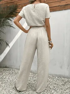 Achteraanzicht van elegante beige tweedelige set met getextureerde top en wijde broek