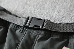 Close-up view of the adjustable plastic buckle and belt on outdoor softshell pants