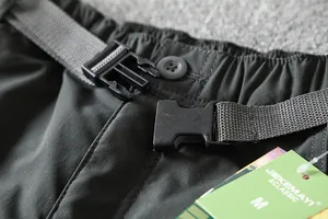 Detailed view of the quick-release buckle and belt on men's outdoor softshell pants