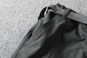 Close-up of men's outdoor softshell pants featuring elastic waistband and woven belt.