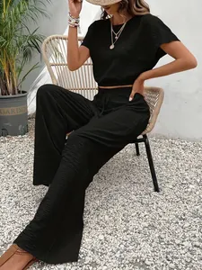 Elegante zwarte tweedelige set met getextureerd T-shirt en broek met wijde pijpen.