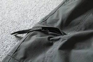 Close-up detail of zipper pocket and durable fabric on men's outdoor softshell pants